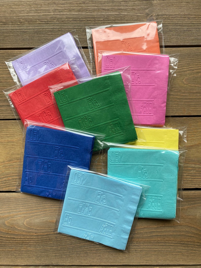 May include: A set of ten colorful paper napkins with a script font design. The napkins are packaged individually in clear plastic bags. The colors include purple, red, green, blue, yellow, and pink.