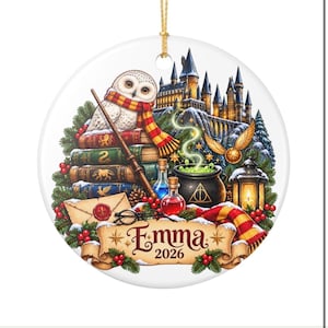 May include: A round white ceramic ornament featuring a snowy castle, a white owl with a red and yellow scarf, stacked books, a magic wand, a cauldron with green smoke, a golden snitch, a lantern, and a scroll with the text Emma 2026.