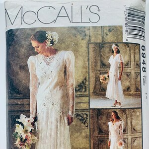 May include: A vintage McCall's pattern for a wedding dress, featuring a lace design with a high neckline and long sleeves. The pattern number is 6948, size 14. The pattern is labeled "Alicyn Exclusives".