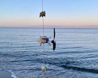 Wind chime with 3 pig propellers and 2 babies with colorful swimming trunks.