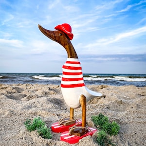 Anatra runner con cappello e infradito a righe rosse e bianche, alta circa 28 cm.