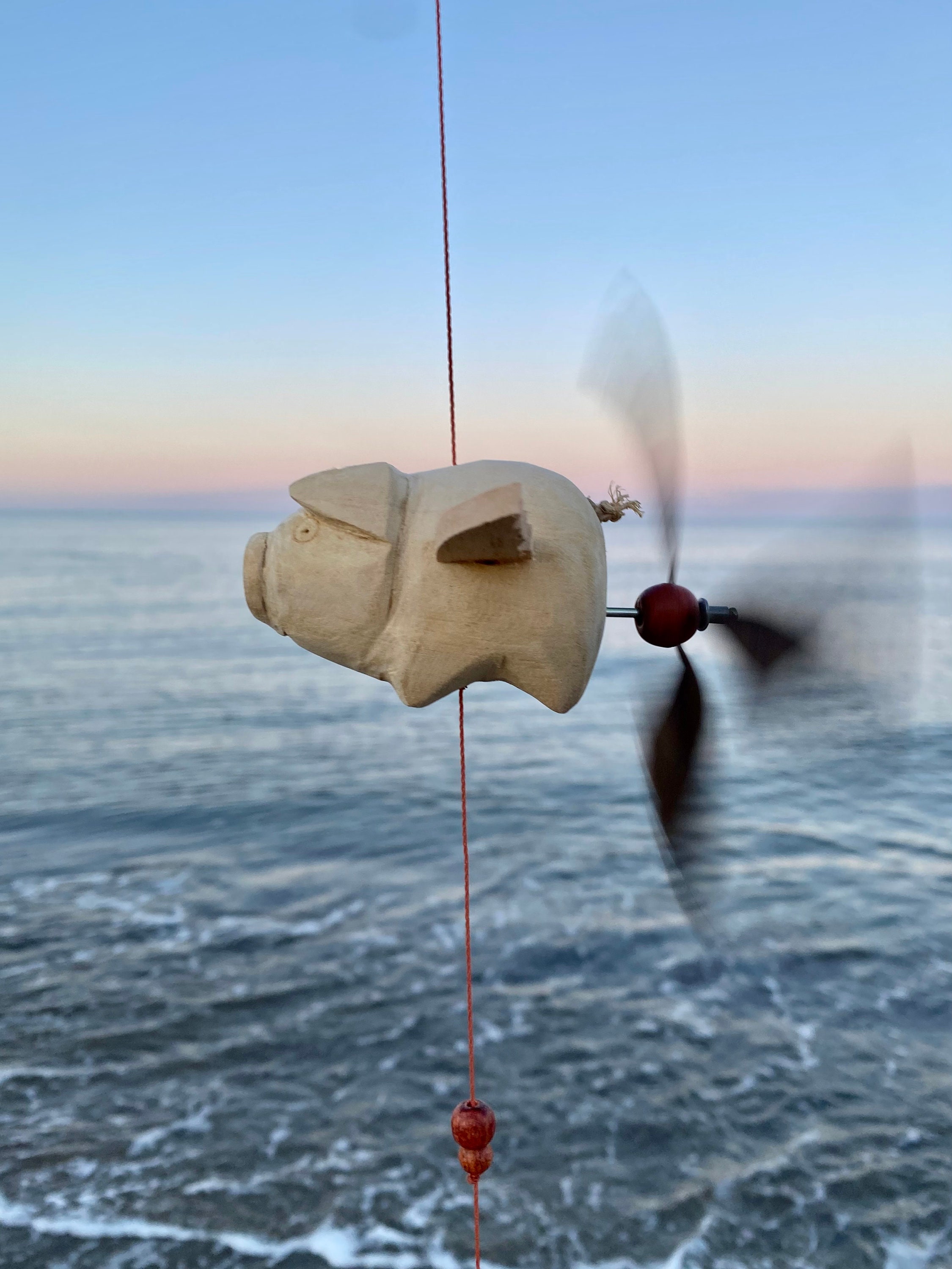 3 pig wind chime made of wood in natural with propeller.