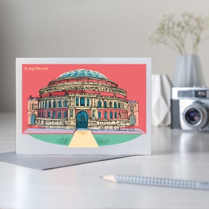 Pu&ograve; includere: Biglietto di auguri con una colorata illustrazione della Royal Albert Hall. L'edificio iconico &egrave; raffigurato in rosso, beige e blu su uno sfondo rosso. Il testo "The Royal Albert Hall" &egrave; visualizzato in alto.