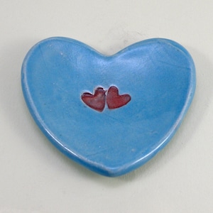 May include: A light blue heart-shaped dish with two red hearts in the center.