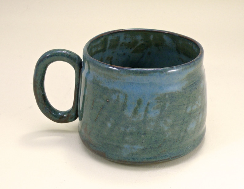 May include: A blue ceramic mug with a handle. The mug has a mottled glaze with a light blue and green color.