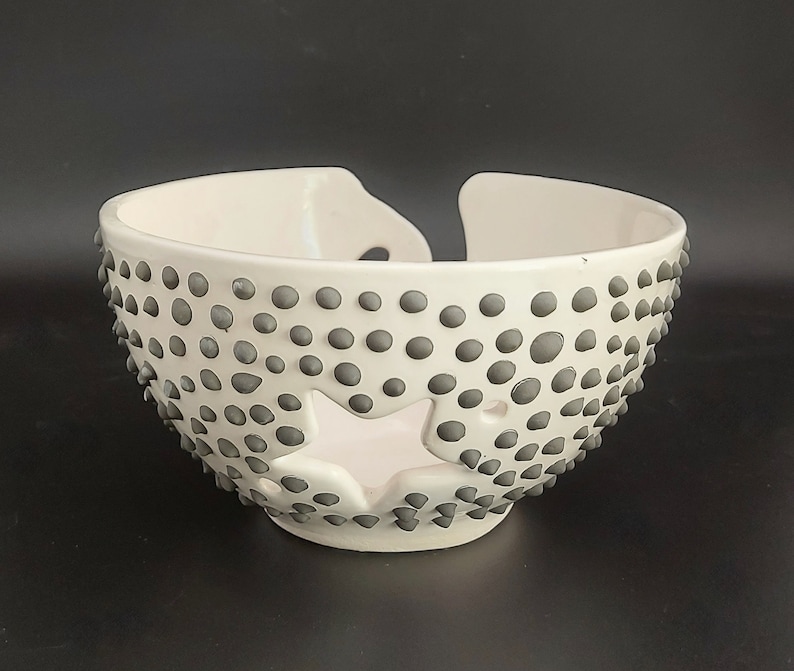 May include: White ceramic bowl with a star-shaped cutout and a textured surface of small gray dots.