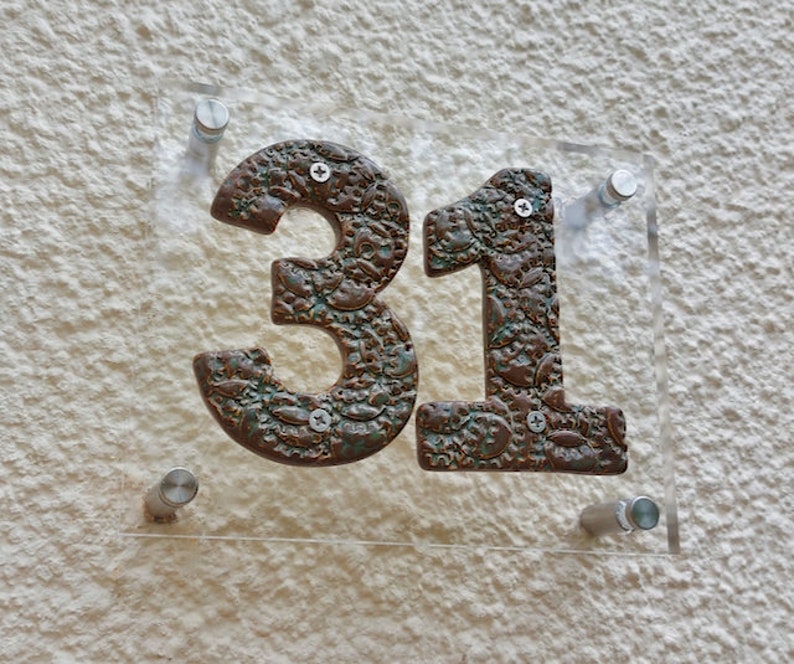 May include: A clear acrylic house number sign with the number 31 in brown with a textured, metallic finish.