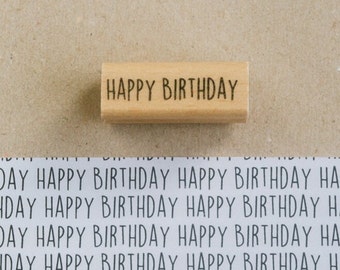 Peut inclure: Un tampon en bois avec le texte "HAPPY BIRTHDAY" imprimé en encre noire.
