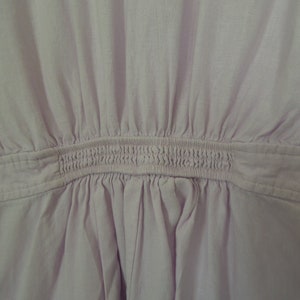 May include: A light purple dress with a gathered waist and a smocked elastic band.