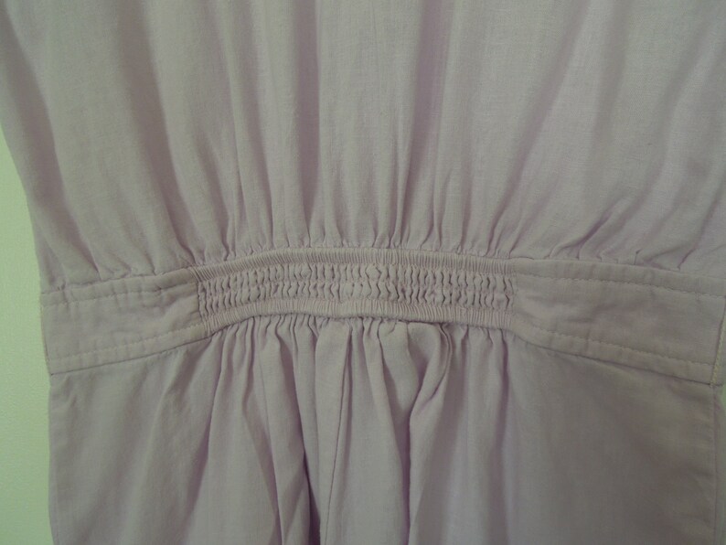 May include: A light purple dress with a gathered waist and a smocked elastic band.