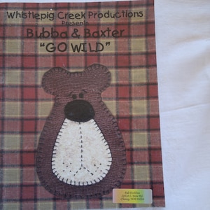May include: A book cover with a red and green plaid background. The title is "Whistlepig Creek Productions Presents Bubba & Baxter "GO WILD"". A brown felt bear with a white felt belly is in the center of the cover.