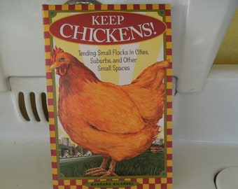 May include: A book cover with a red, yellow, and white checkered background. The title is "Keep Chickens!" in large, bold letters. The subtitle is "Tending Small Flocks in Cities, Suburbs, and Other Small Spaces." An illustration of a brown hen is featured on the cover.