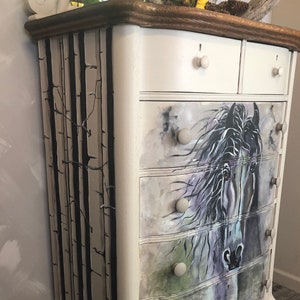 Puede incluir: C&oacute;moda blanca pintada con cinco cajones. Los cajones est&aacute;n decorados con una ilustraci&oacute;n de un caballo en blanco y negro. El lateral de la c&oacute;moda est&aacute; pintado con un dise&ntilde;o de &aacute;rbol de abedul en blanco y negro.