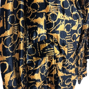 May include: A black velvet blazer with a gold abstract print. The blazer has a single button closure and two pockets.