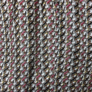 May include: A brown fabric with a repeating pattern of white, black, and pink stylized floral shapes.