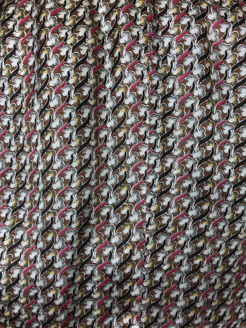 May include: A brown fabric with a repeating pattern of white, black, and pink stylized floral shapes.