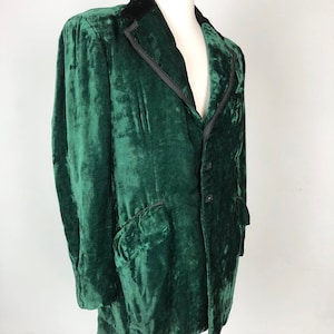 May include: A dark green velvet jacket with a black velvet collar and a single button closure. The jacket has a classic design and is in good condition.
