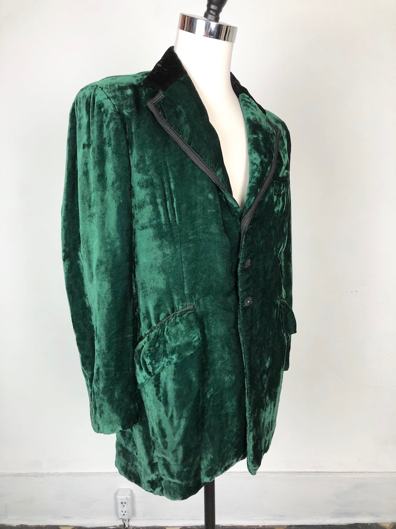 May include: A dark green velvet jacket with a black velvet collar and a single button closure. The jacket has a classic design and is in good condition.