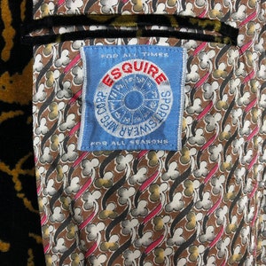 May include: A blue and white label with the text "Esquire Sportswear for all times for all seasons" and a circular design with a sun and the words "All Weather" and "Sportswear" around it.
