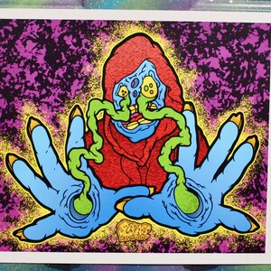 May include: A colourful illustration of a creature with a red hooded cloak and blue hands. The creature has a green, slimy face with large, round eyes. The background is a dark purple and black with yellow and green speckles. The text "ZAP! CREATIONS" is at the bottom of the image.