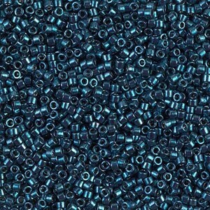 May include: A close-up shot of a pile of small, cylindrical beads in a deep teal color. The beads are densely packed, creating a textured surface. These beads are likely used for jewelry making or other craft projects.
