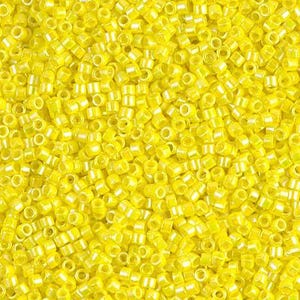 May include: Close-up of a pile of small, cylindrical yellow beads. The beads are uniform in size and shape, with a slightly translucent appearance. They are scattered randomly, creating a textured surface.