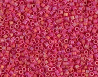 May include: A close-up view of a large quantity of small, round, pink and orange seed beads. The beads have a slightly iridescent finish.