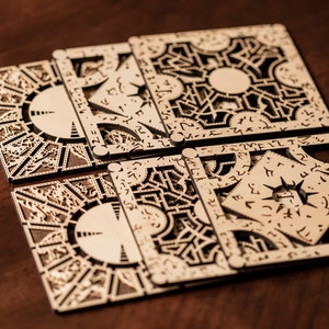 May include: Six intricately designed wooden puzzle boxes with geometric patterns and symbols. The boxes are arranged on a dark wooden surface, showcasing the detailed laser-cut designs. The overall aesthetic is a warm, natural tone.