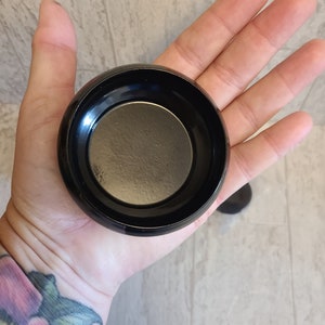 May include: A black round metal candle holder with a smooth, shiny finish.