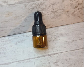 May include: A small amber glass bottle with a black dropper top. The bottle is about 1 inch tall and has a narrow neck.