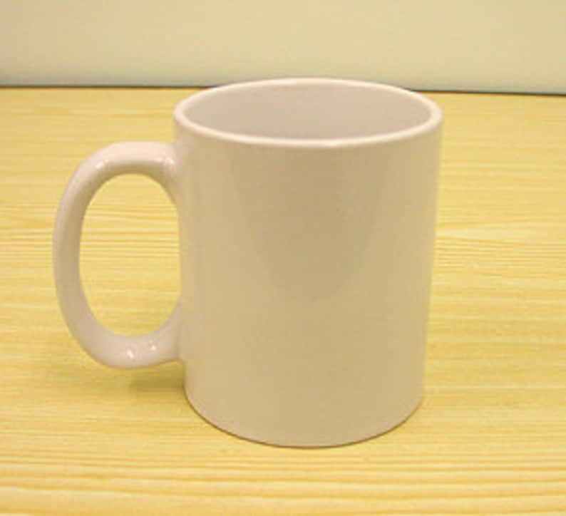 K&ouml;nnte beinhalten: Ein schlichter wei&szlig;er Keramikbecher mit glatter, gl&auml;nzender Oberfl&auml;che und einem geschwungenen Henkel auf der linken Seite. Der Becher hat einen zylindrischen K&ouml;rper mit einer weiten, offenen Oberseite und einem festen Boden f&uuml;r Getr&auml;nke.