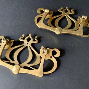 May include: Two ornate brass door handles with a decorative design. The handles are in the shape of a stylized flower with a central bulb and intricate details.