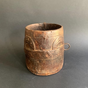 Peut inclure: Un seau en bois rustique avec un motif sculpté et une poignée en métal. Le seau est brun et a un aspect usé.