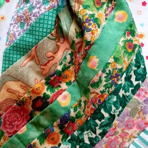 Può includere: Una borsa a cordoncino in tessuto a righe verde e bianche con un design patchwork di motivi floreali e fogliari. La borsa ha un nastro verde con la scritta "Trifis" su di esso.