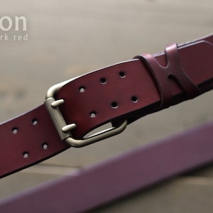 May include: A dark red leather belt with a brass buckle. The belt has a "legion dark red" label.