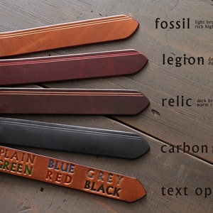 Peut inclure: Cinq lani&egrave;res en cuir de diff&eacute;rentes couleurs et textures, &eacute;tiquet&eacute;es avec des noms comme "fossil", "legion", "relic" et "carbon". Les lani&egrave;res pr&eacute;sentent un d&eacute;tail de couture subtil. Une petite lani&egrave;re en cuir en bas porte les mots "PLAIN GREEN", "BLUE RED" et "GREY BLACK" en diff&eacute;rentes couleurs.