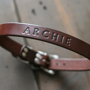 Peut inclure: Un collier de chien en cuir marron avec le nom "ARCHIE" grav&eacute; en lettres noires.