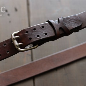 May include: A dark brown leather belt with a silver buckle and multiple holes. The belt has a distressed look and is labeled "relic dark brown".