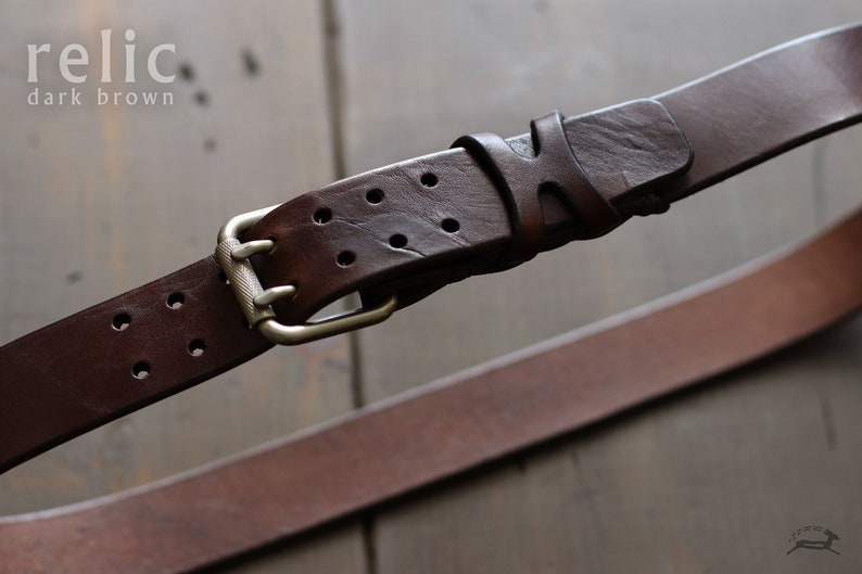 May include: A dark brown leather belt with a silver buckle and multiple holes. The belt has a distressed look and is labeled "relic dark brown".