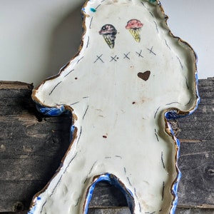 May include: White ceramic plate shaped like a person with blue and gold trim. The plate has two ice cream cones painted on it, along with the text "XXX" and a heart.