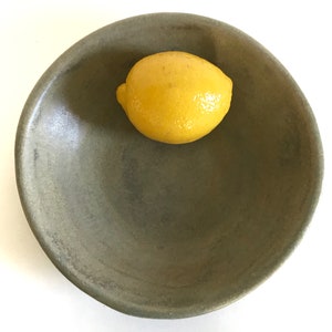 May include: A green ceramic bowl with a yellow lemon inside.