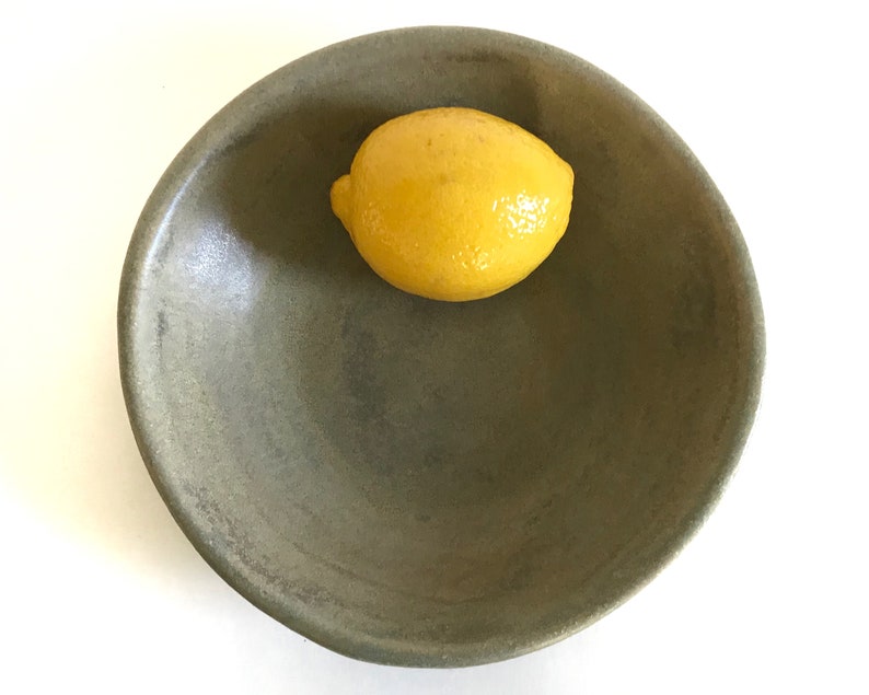 May include: A green ceramic bowl with a yellow lemon inside.