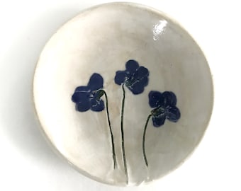 May include: A white ceramic dish with three blue flowers painted on it.