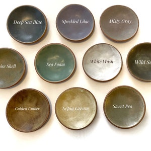 May include: Ten small ceramic dishes in various shades of green, blue, brown, and gray. The dishes are labeled with names like "Deep Sea Blue", "Speckled Lilac", "Misty Gray", "White Wash", "Wild Sage", "Tortoise Shell", "Sea Foam", "Sweet Pea", "Golden Umber", and "Sepia Cream".