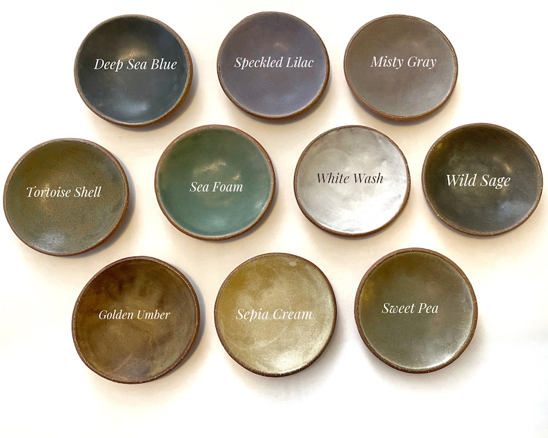 May include: Ten small ceramic dishes in various shades of green, blue, brown, and gray. The dishes are labeled with names like "Deep Sea Blue", "Speckled Lilac", "Misty Gray", "White Wash", "Wild Sage", "Tortoise Shell", "Sea Foam", "Sweet Pea", "Golden Umber", and "Sepia Cream".
