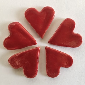 May include: Five red ceramic heart-shaped tiles arranged in a circle.