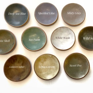 May include: Ten small ceramic dishes in various shades of green, blue, brown, gray, and white. Each dish has a different color glaze and is labeled with a color name.