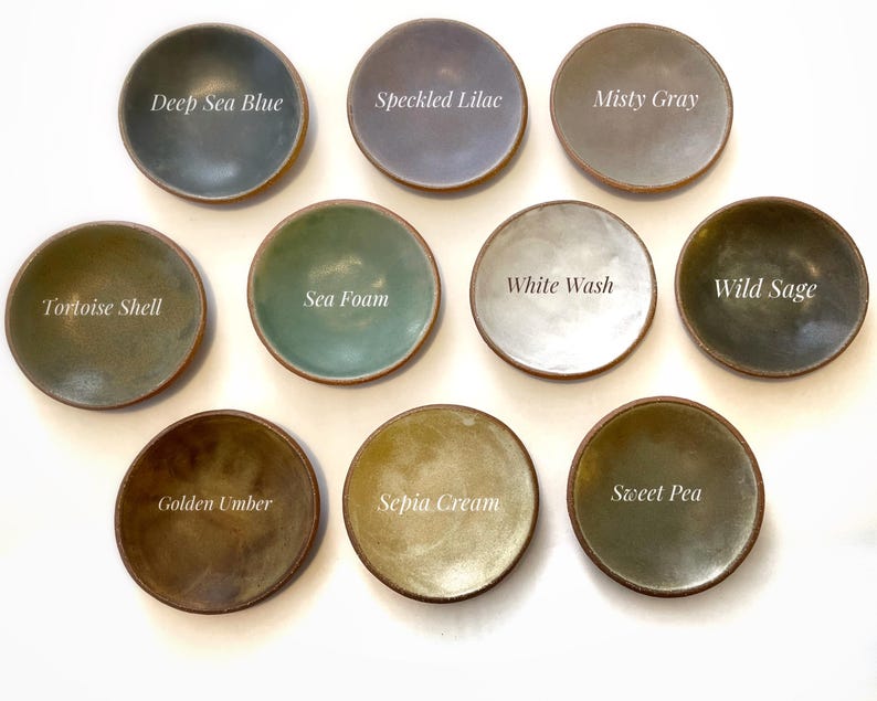 May include: Ten small ceramic dishes in various colours, including deep sea blue, speckled lilac, misty grey, white wash, sea foam, wild sage, tortoise shell, sweet pea, golden umber, and sepia cream. Each dish has a unique glaze and colour.