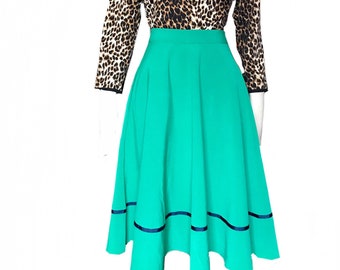 May include: A teal green skirt with a black trim around the hem. The skirt is full and has a high waist. A leopard print top is worn over the skirt.