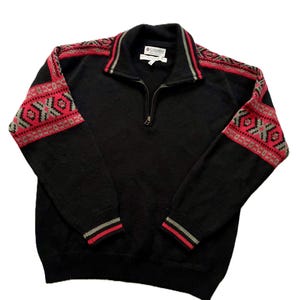 May include: Black zip-up sweater with red and gray geometric patterns on the shoulders and sleeves. The collar and cuffs have red and gray stripes. The sweater has a small Columbia logo.